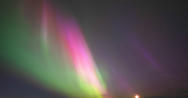 Intense red, pink, and green northern lights in bands.